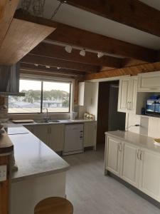 Una cocina con gabinetes blancos y una ventana grande. en The Lakehouse Lochsport, en Lock Sport