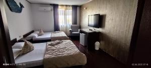 a hotel room with two beds and a tv at Vila Hera in Eforie Sud