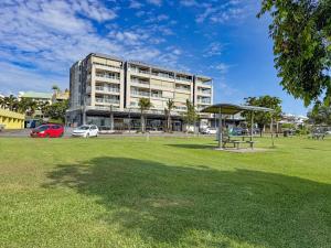 Un gran edificio con un parque enfrente. en Rivergrande Apartment, en Innisfail