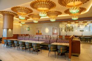 a restaurant with tables and chairs and chandeliers at Hotel Grand Arose in Ahmedabad