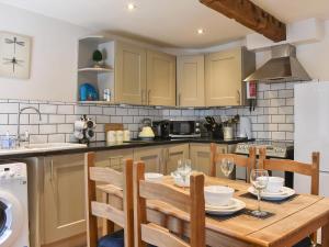a kitchen with a wooden table and chairs in a kitchen at Cartwheel Cottage in Hawes