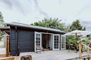 a black cottage with a deck and an umbrella at The Barn Bellingen in Bellingen +12 photos