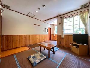 a living room with a table and a tv at Pension Alps Hakuba in Hakuba