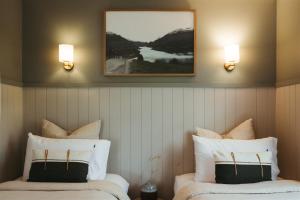 two beds in a room with two lights on the wall at The Woodshed - Hot Stone Sauna & Ice Bath in Robe