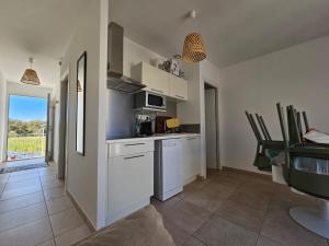 a kitchen with white cabinets and a table with chairs at T3 bord de mer en Corse N130 in Linguizzetta