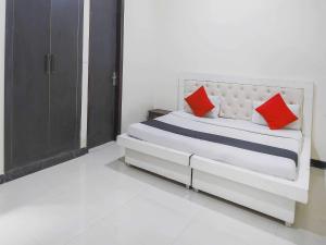 a white bed with red pillows in a room at Hotel O GRANDEUR HOTEL in Indirapuram