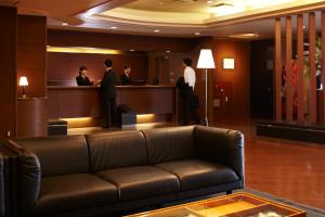 a lobby with a couch and people standing at a bar at Hirosaki Plaza Hotel in Hirosaki