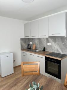 a kitchen with white cabinets and a black stove top oven at Apartmani Pervan 2 in Livno