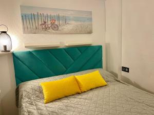 a bed with a green headboard and a yellow pillow at Apartamento Mar y Montaña in Cullera