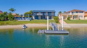 a dog sitting in the water next to a dock at Pandanus - Spacious Waterfront Escape with Private Pontoon & Pool - Holiday Yamba in Yamba