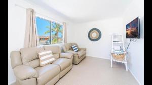 a living room with a couch and a window at Pandanus - Spacious Waterfront Escape with Private Pontoon & Pool - Holiday Yamba in Yamba