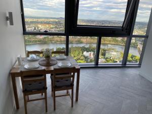 a table and chairs in a room with large windows at Queens Wharf 50th Floor in Brisbane