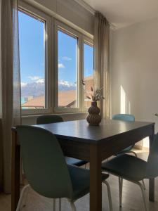 a dining room with a table and chairs and windows at Amalia-Levico Terme Apartment in Levico Terme
