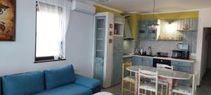 a living room with a blue couch and a kitchen at Anthic 7 Apartment 3 in Sozopol