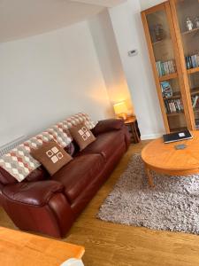 a living room with a brown leather couch and a table at The Cottage in Redruth