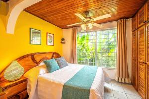 a bedroom with a bed with a ceiling fan and a window at Villa Jaco Sol in Jacó +50 photos