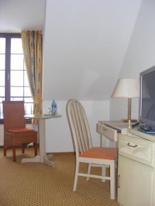 um quarto com uma secretária, uma televisão e uma cadeira em Hotel Schwartze em Weimar