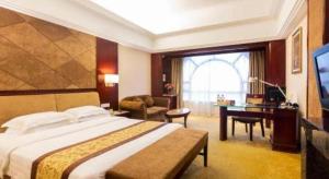 une chambre d'hôtel avec un grand lit et un bureau dans l'établissement Vienna International Hotel Dongguan Changping Tian'ehu Road, à Dongguan