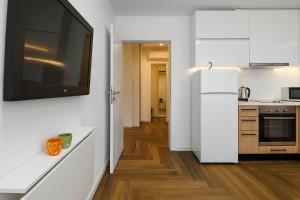 a kitchen with white cabinets and a tv on the wall at North Panoramic Apartment in the art district of Kapana in Plovdiv