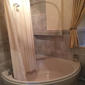 ein Bad mit einer Badewanne und einem Duschvorhang in der Unterkunft Lovat House in Crieff
