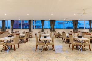 a dining room with tables and chairs and windows at Galaxy Royal Suites in Bangalore