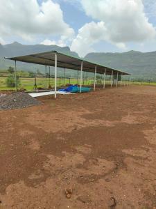 a pavilion with a roof on a dirt field at Shikhar camping bhandardara in Bhandāra