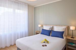 Un dormitorio con una gran cama blanca con almohadas azules. en Zenitude Quality Aparthotel Rouen, en Rouen