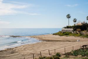 una spiaggia sabbiosa con palme e l'oceano di Villa La Dorada a Mijas Costa