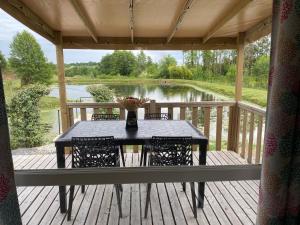 a table on a deck with a view of a lake at Belle location face à l'étang in Landouzy-la-Cour
