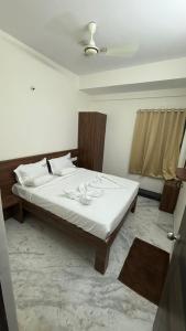 Blue Bell Residency Yeswanthpur Railway Station في بانغالور: غرفة نوم بها سرير بملاءات بيضاء ونافذة