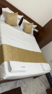 Blue Bell Residency Yeswanthpur Railway Station في بانغالور: سرير مع ملاءات ووسائد باللونين الأبيض والذهبي