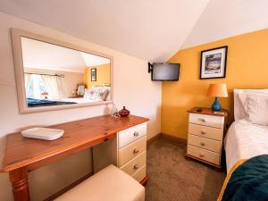 a bedroom with a desk with a mirror and a bed at Tramways Holiday Cottage in Carnbrea