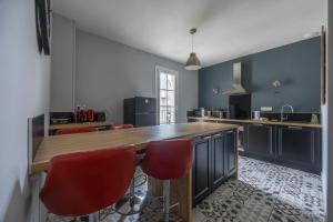 a kitchen with a wooden counter and red chairs at Le Soleil de Saint Patrice in Bayeux