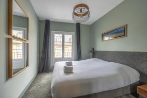 a bedroom with a large bed and two windows at Le Soleil de Saint Patrice in Bayeux