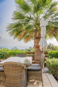 un patio avec une table, des chaises et un palmier dans l'établissement Villa Pleiades - sea views, private pool & hot tub, à Kouklia
