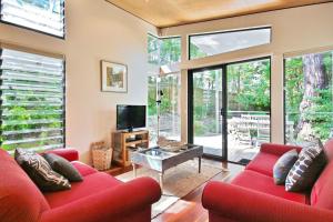 ein Wohnzimmer mit roten Sofas und einem TV in der Unterkunft Hyams Retreat Hyams Beach in Hyams Beach