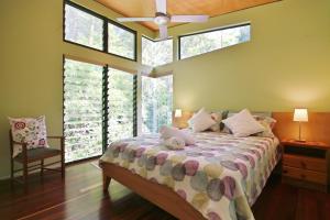 Schlafzimmer mit einem Bett mit Fenstern und einem Ventilator in der Unterkunft Hyams Retreat Hyams Beach in Hyams Beach