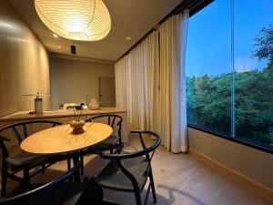 a dining room with a table and chairs and a large window at Citrus House Phra-Arthit in Bangkok
