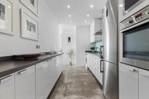 a kitchen with white cabinets and a stainless steel refrigerator at Casa Sol - Impresionantes vistas al mar in Torremolinos