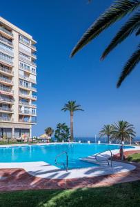 a swimming pool with palm trees in front of a building at Casa Sol - Impresionantes vistas al mar in Torremolinos