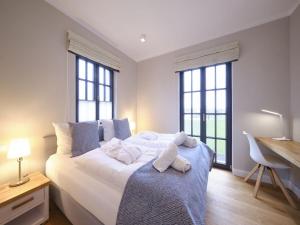 1 Schlafzimmer mit einem großen weißen Bett und 2 Fenstern in der Unterkunft Reetland am Meer - LuxusPlus Reetdachvilla mit 4 Schlafzimmern, Sauna und Kamin G13 in Dranske