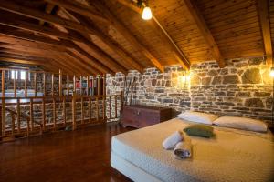 a bedroom with a bed in a stone wall at Echo Traditional House - Ηχώ Παραδοσιακό Σπίτι in Émbonas