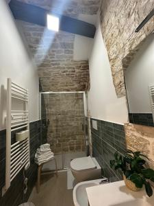a bathroom with a toilet and a stone wall at Antica Roma 122 in Sammichele di Bari