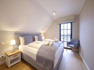 ein Schlafzimmer mit einem großen Bett und einem blauen Stuhl in der Unterkunft Reetland am Meer - LuxusPlus Reetdachvilla mit 4 Schlafzimmern, Sauna und Kamin G14 in Dranske