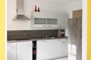 Una cocina blanca con gabinetes blancos y un fregadero. en Villa Liselotte, en Fürstenberg-Havel