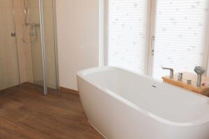 Una bañera blanca en un baño con ducha. en Villa Liselotte, en Fürstenberg-Havel
