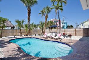 a swimming pool with chairs and palm trees at Family Tides in Fort Myers Beach
