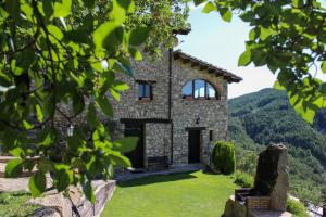 a stone house on a hill with mountains in the background at MAS MEROLLA CASA PARA DESCANSO FAMILIAR in Gombreny