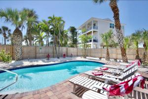 a swimming pool with lounge chairs and a house at Family Tides in Fort Myers Beach
