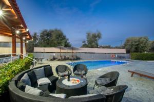 een terras met een tafel en stoelen naast een zwembad bij Villa Di Georgia in Afantou